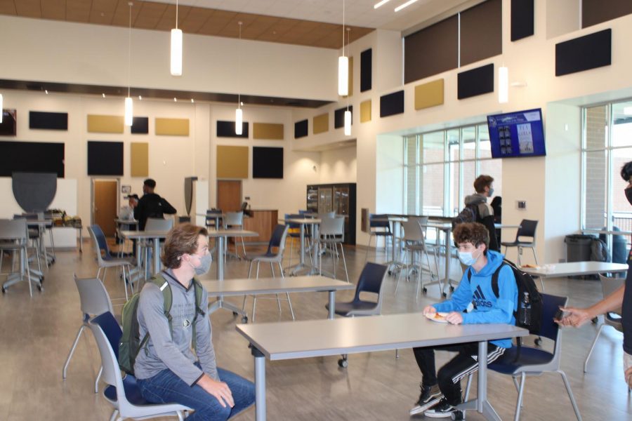 Two students sit together during a socially-distanced lunch. Tables are spaced apart and only two people may sit together as they eat. 