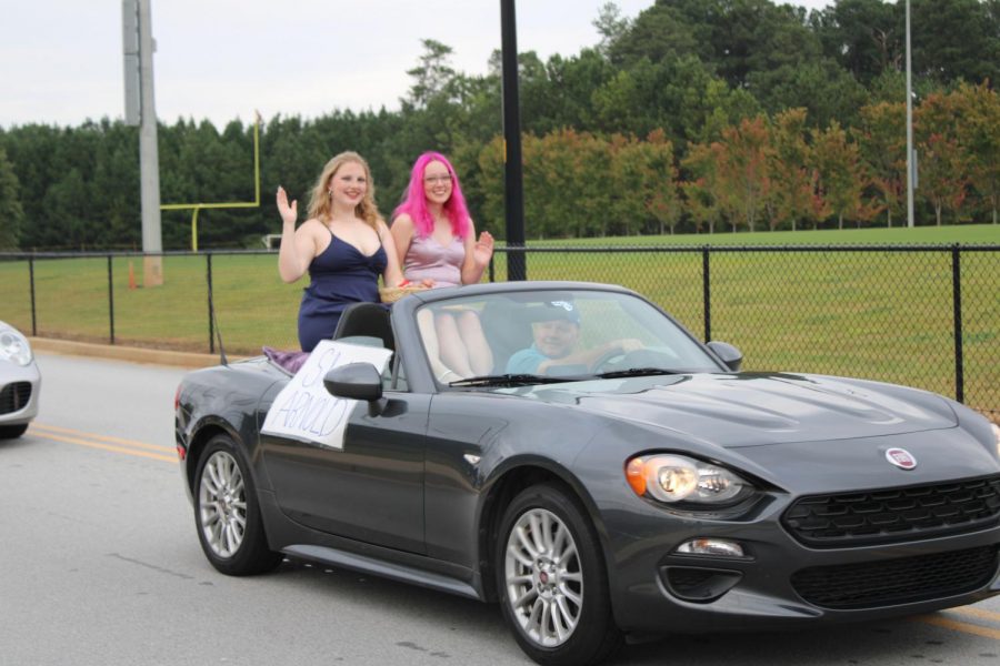 Shelby Arnold (12) and Julianna Egge (12), two Homecoming queen candidates, ride through the parade.