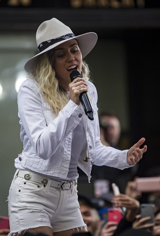 Miley Cyrus singing in front of an audience.
