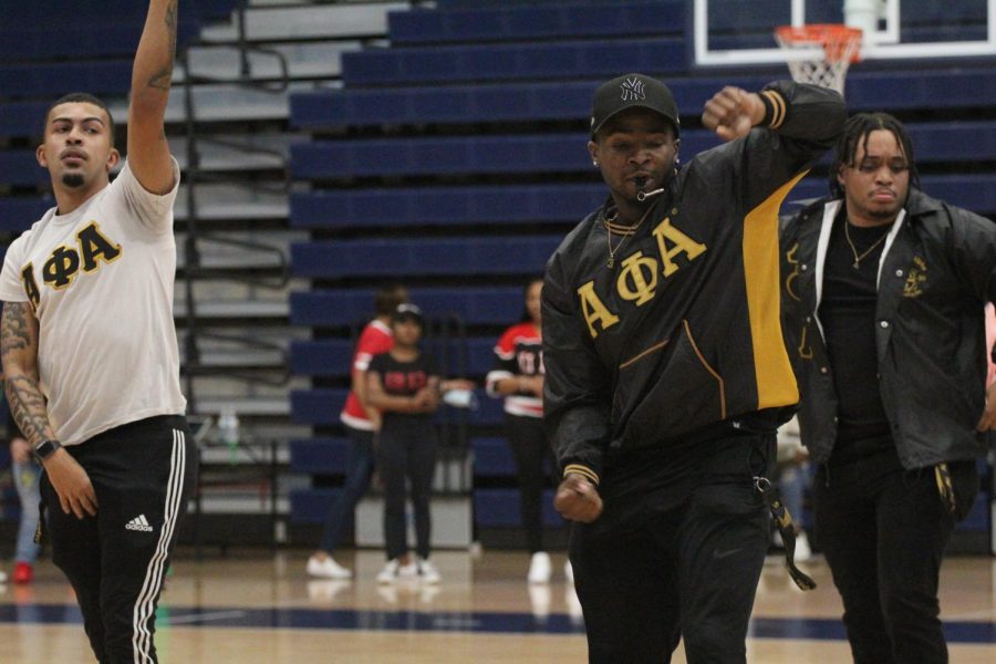 An AOA fraternity member, wearing the fraternitys signature gold and black, dances along with other members. 