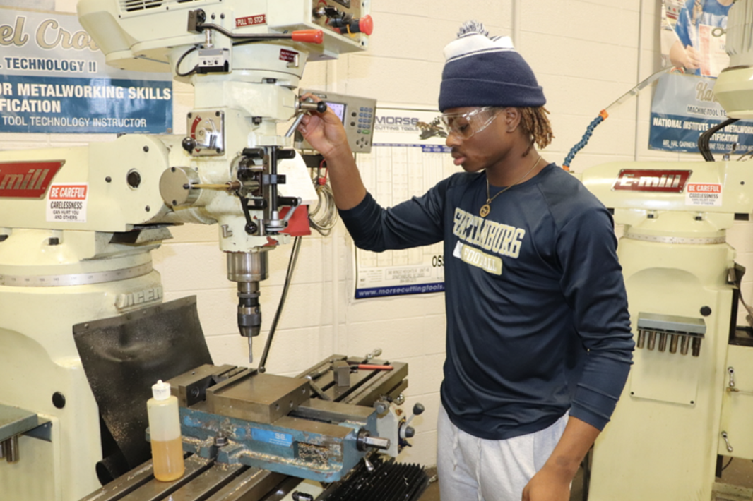 Joshua Taliaferro (10) operates a milling machine, drilling a hole in his tap handle project. 