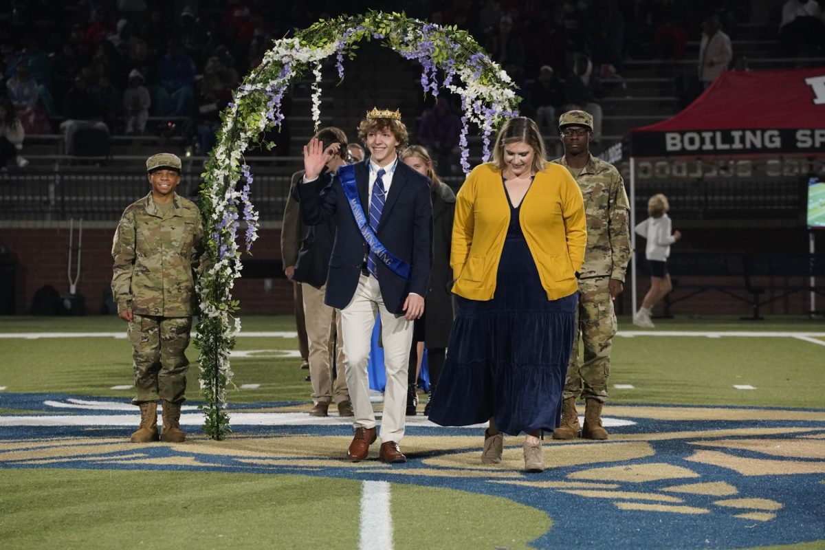 Student Council adviser Cassidy Holt and Homecoming King Seth Miller (12) strut down the field.