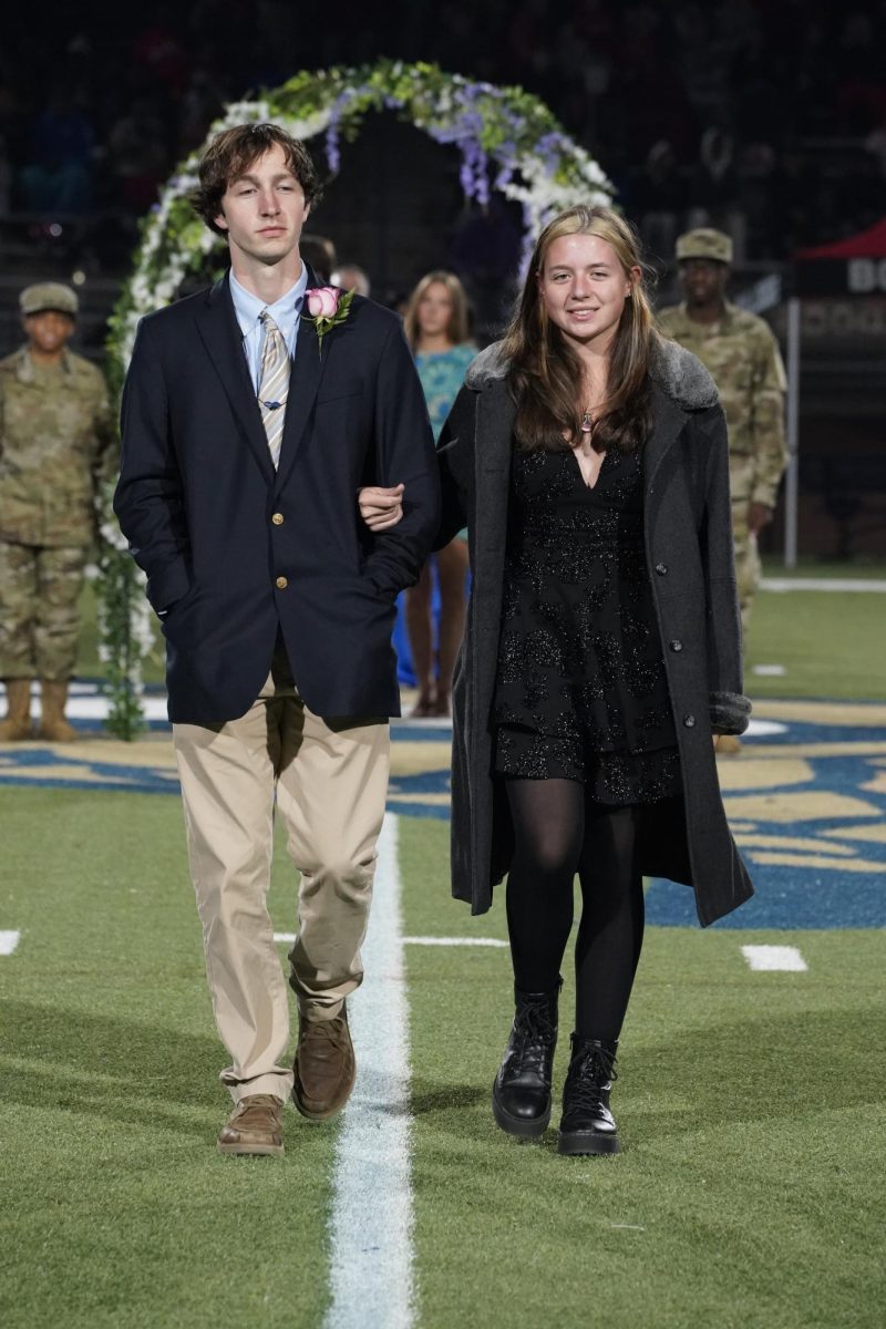 Halle Abbott (12) and her escort smile as they walk down the football field.