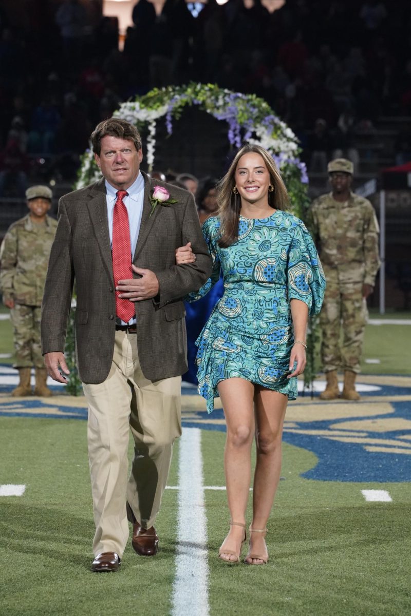 Maggie Akridge (12) is all smiles as she walks down the field with her father as her escort.