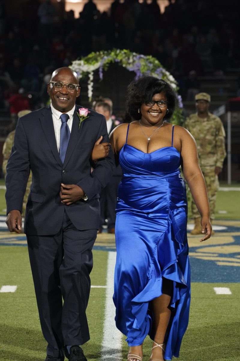 Da'Ranesha Boyd (12) smiles alongside her escort as she is introduced to the Homecoming crowd.