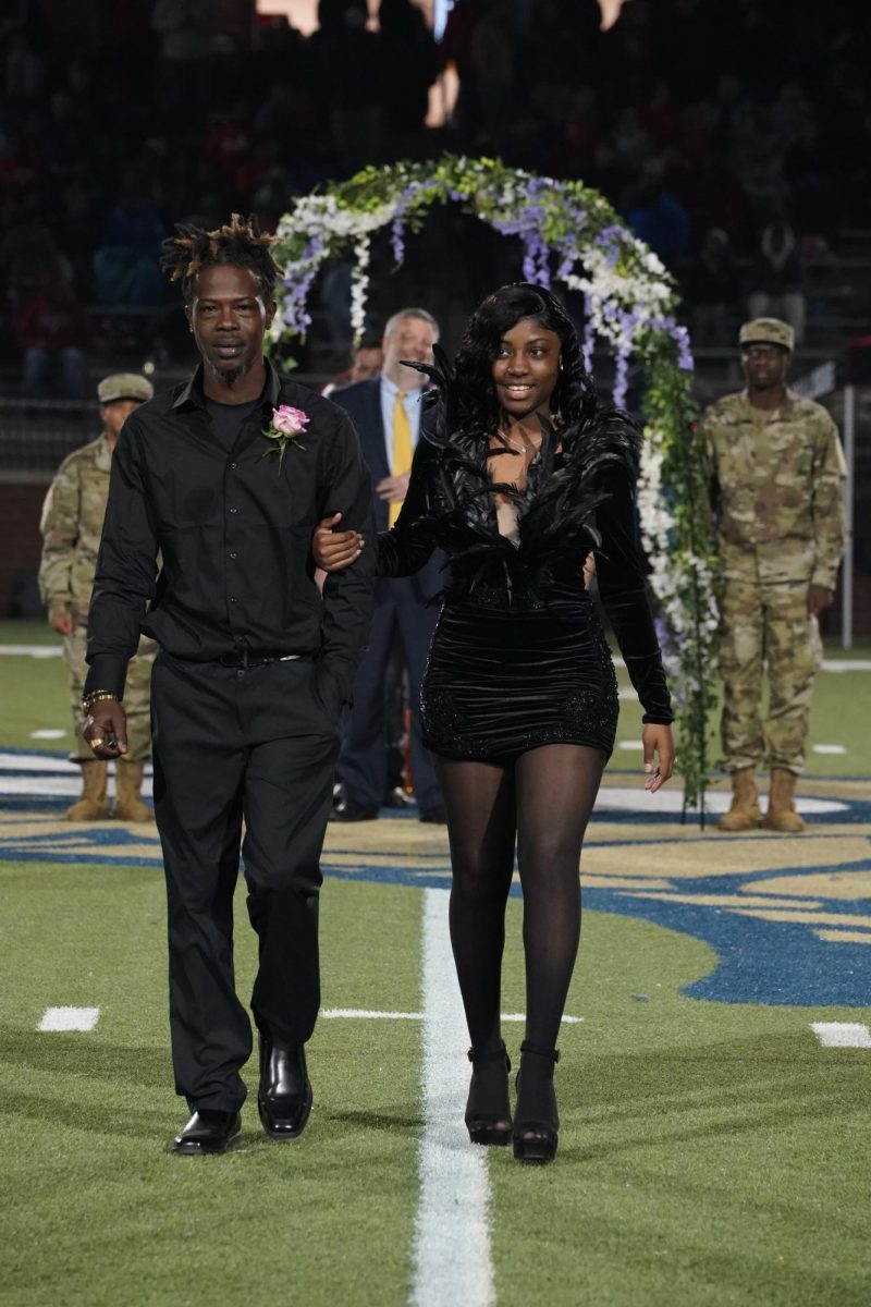 Amani Dowdle (12) looks lovely on the arm of her escort in front of the crowd.