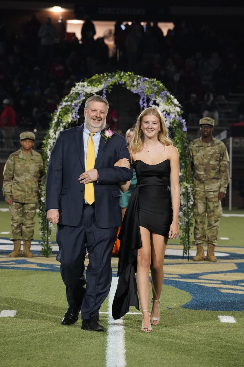 Lillie Henson (12) and her father smile as she is escorted down the field. 