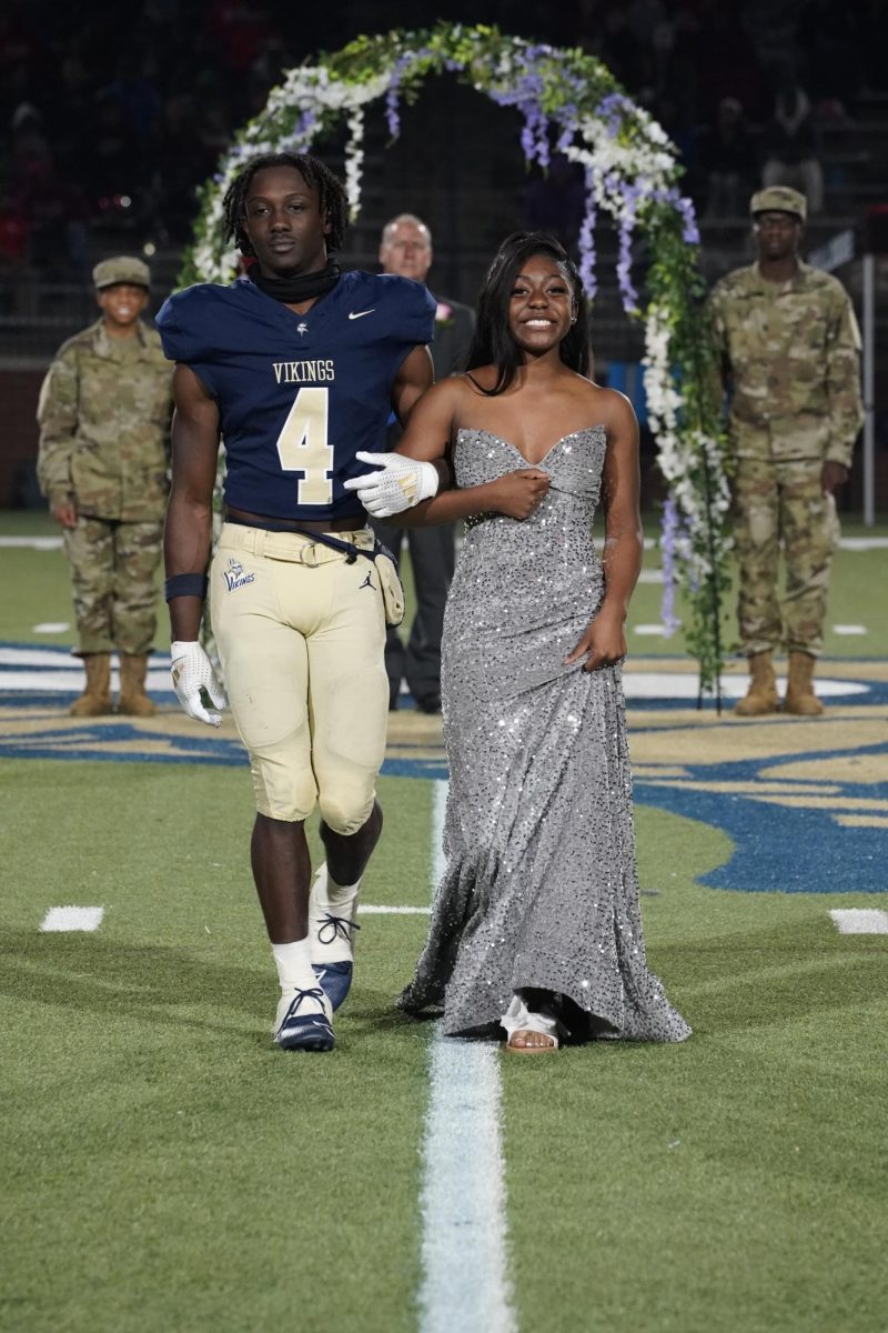 Nikia Tinsley (12) shows off her smile as football player Calvin Choice escorts her across the field.