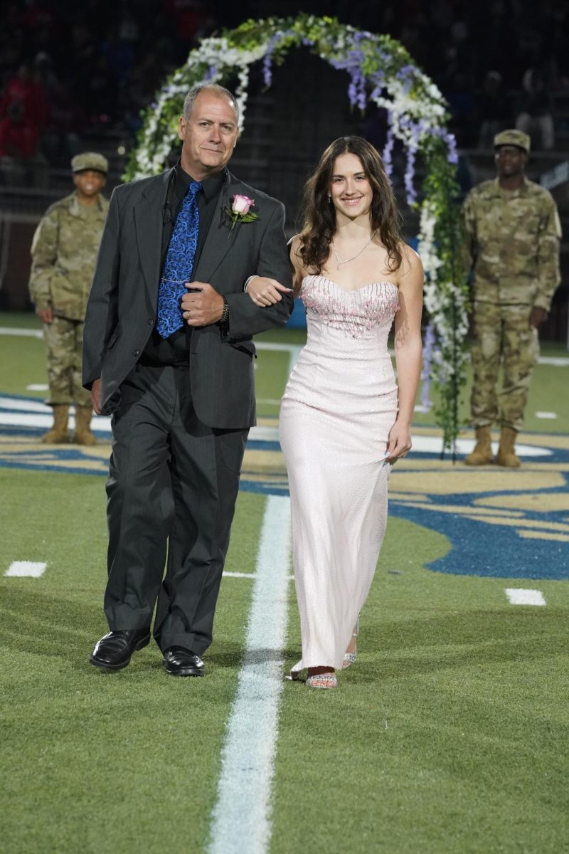 Jennifer Waddle (12) struts down the field, escorted by her father.