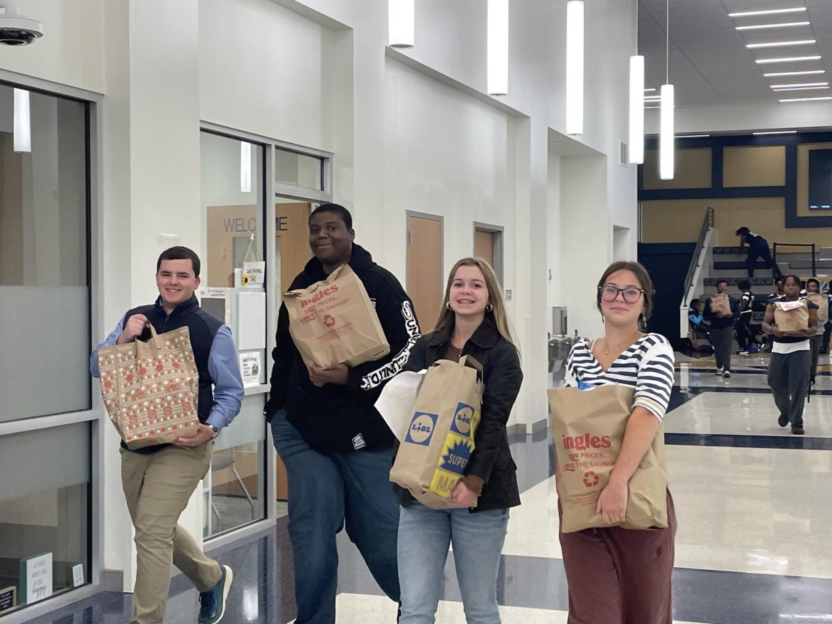 Students smile for a photo while transporting "Thanksgiving bags."