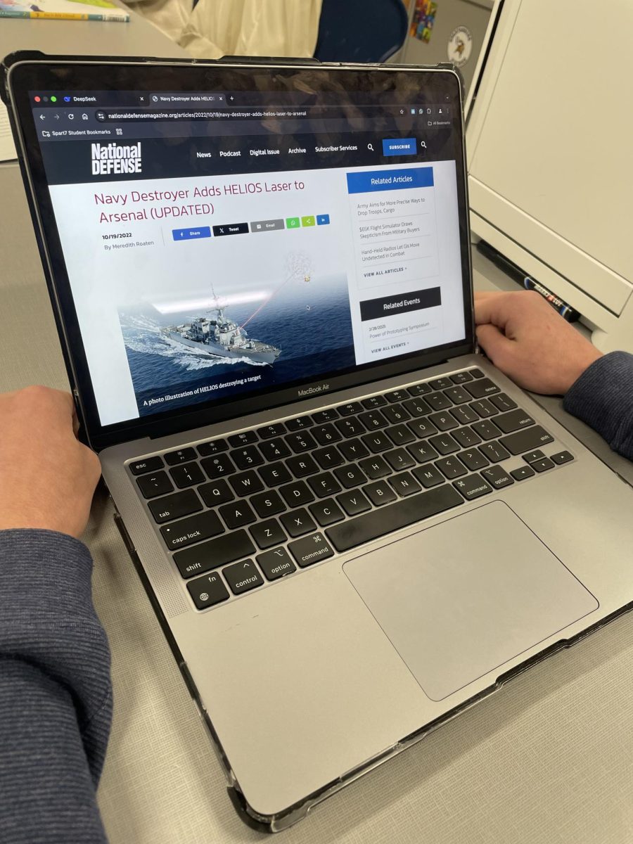 A student reads an article about the HELIOS weapon to find more information about anti-drone technology. 