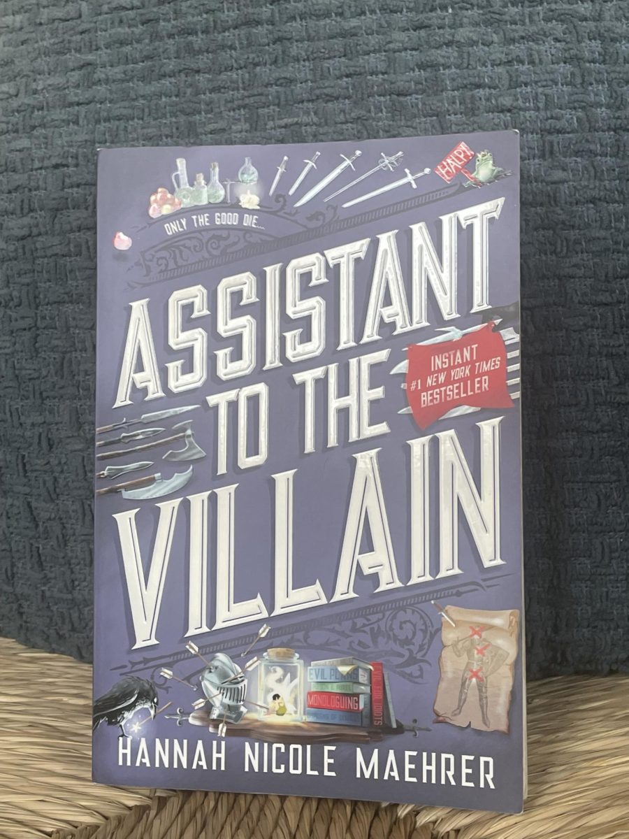 A copy of the romantic fantasy book "Assistant to the Villain" by Hannah Nicole Maehrer. 
